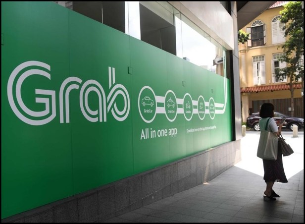 Large street-level billboard ad for a Southeast Asian ride-hailing app.